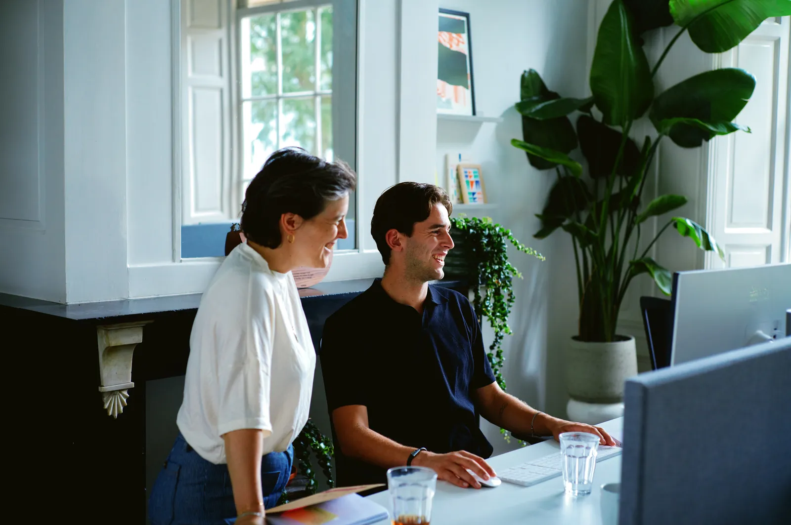 Twee collega's overleggen achter een monitor