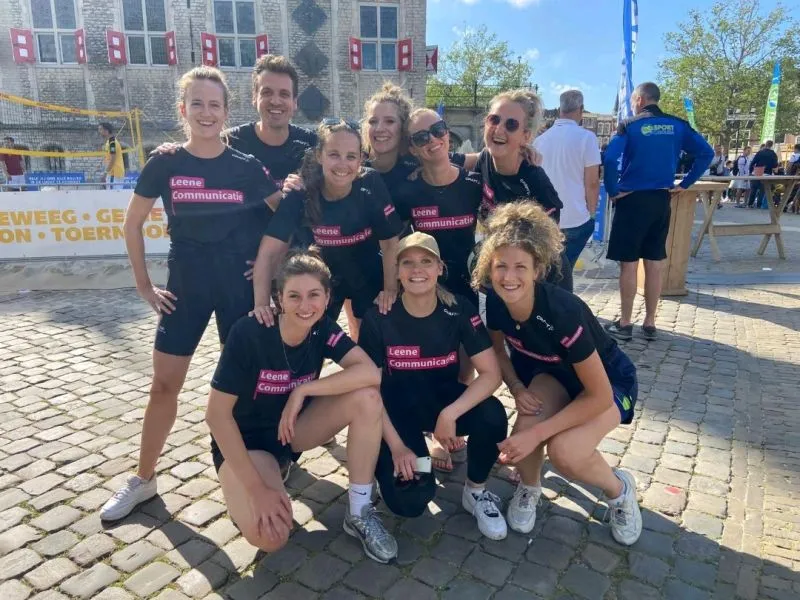 Groepsfoto van collega's in sportkleding na een hardloopevenement.
