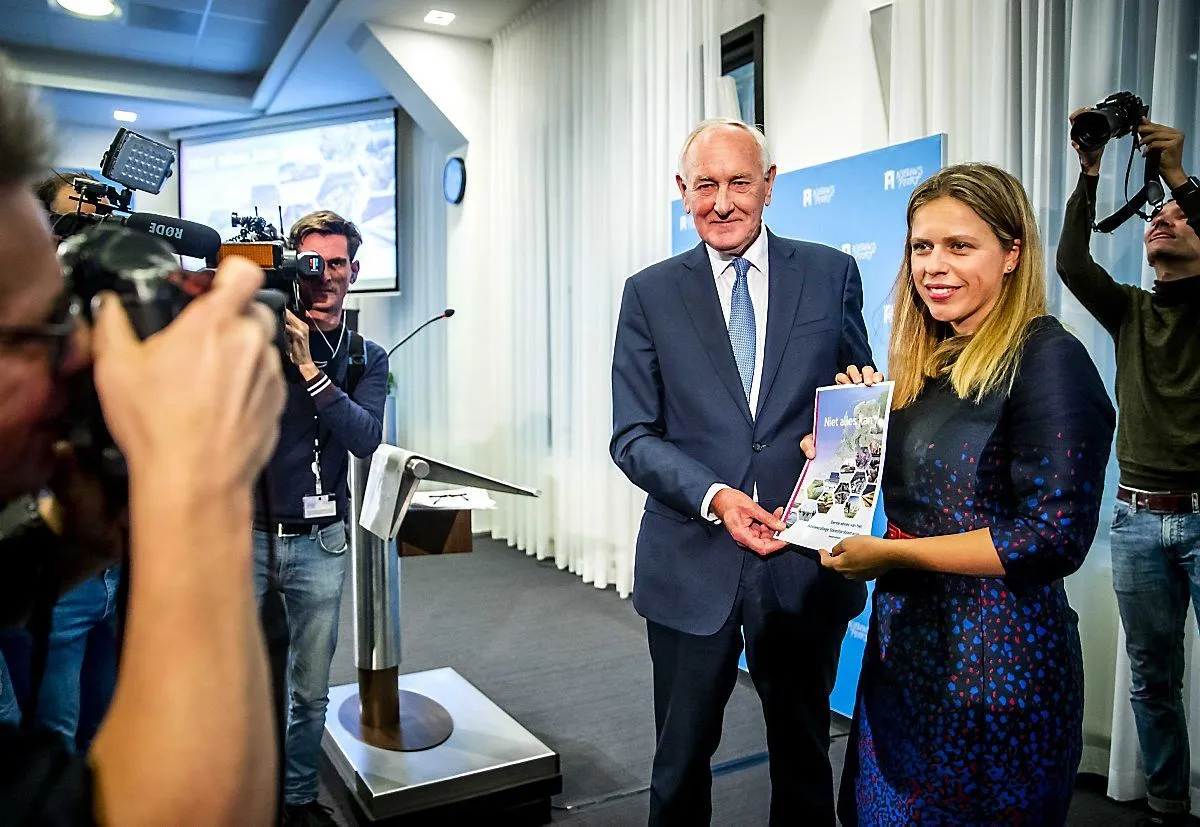 Een rapport wordt overhandigd voor een rij camera's en fotografen.
